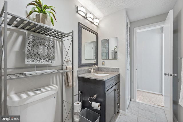 bathroom featuring a textured ceiling, vanity, and toilet