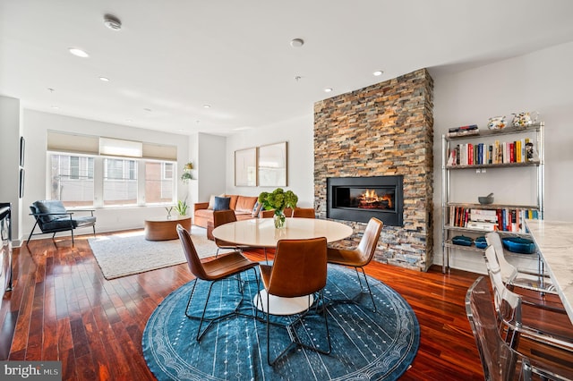 dining area with dark hardwood / wood-style flooring and a stone fireplace