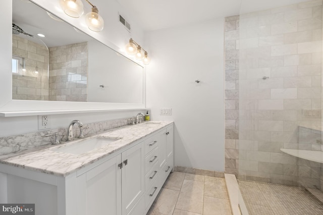 bathroom with tile patterned floors, a tile shower, and vanity