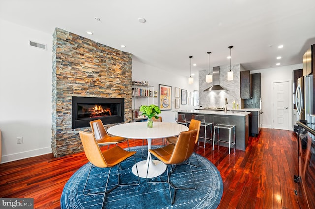 dining area featuring a fireplace, dark hardwood / wood-style flooring, and sink