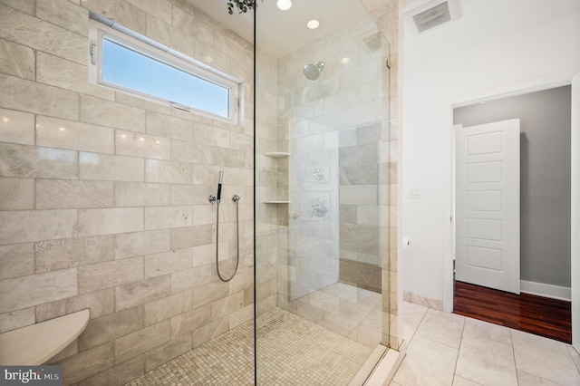 bathroom featuring tiled shower and wood-type flooring