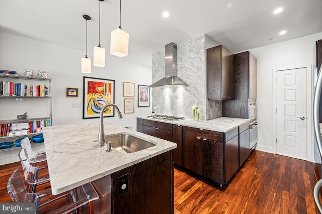 kitchen featuring wall chimney range hood, light stone countertops, dark hardwood / wood-style floors, and sink