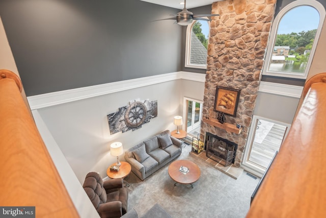 living room with a stone fireplace and ceiling fan