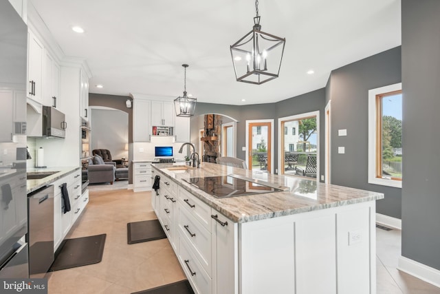 kitchen featuring pendant lighting, white cabinets, light stone countertops, and a large island with sink