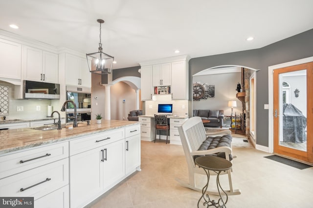 kitchen featuring light stone counters, decorative light fixtures, and white cabinetry