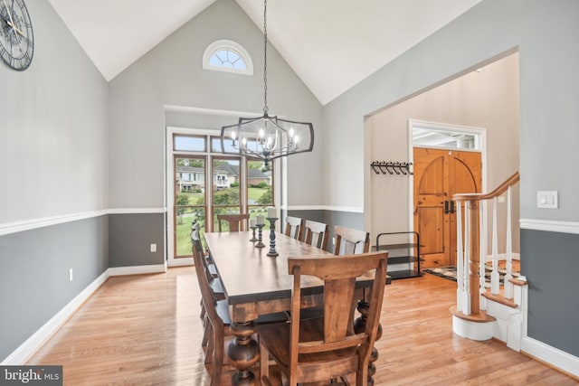 dining space with light hardwood / wood-style flooring, a chandelier, and high vaulted ceiling