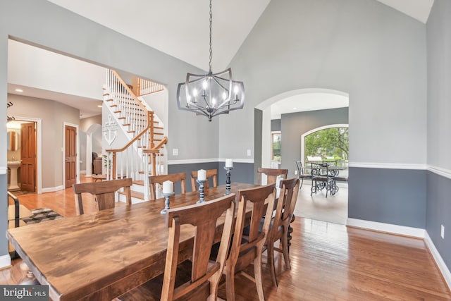 dining space with light hardwood / wood-style flooring, a notable chandelier, and high vaulted ceiling