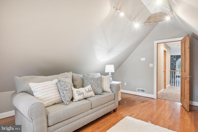 living room featuring vaulted ceiling, hardwood / wood-style floors, and track lighting