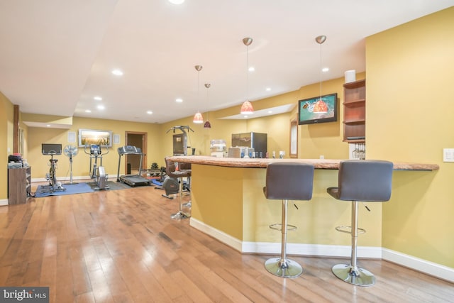 kitchen with light hardwood / wood-style floors, a kitchen breakfast bar, hanging light fixtures, and kitchen peninsula