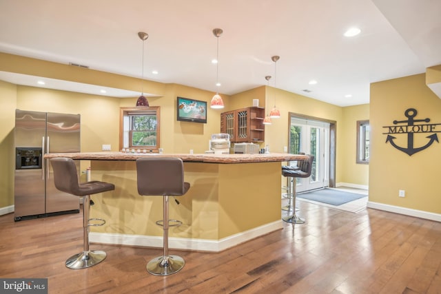 kitchen featuring pendant lighting, a kitchen breakfast bar, plenty of natural light, and stainless steel fridge