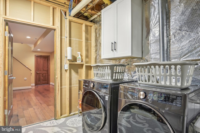 clothes washing area featuring light hardwood / wood-style flooring, cabinets, and washing machine and clothes dryer