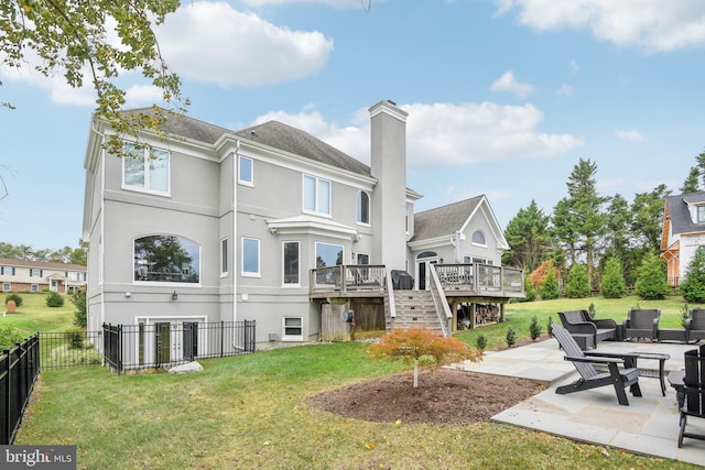 back of house featuring a lawn, a deck, and a patio area