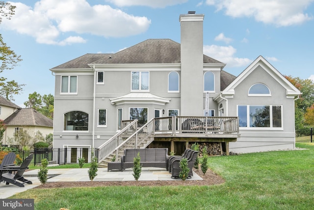 back of property with a lawn, a wooden deck, and a patio area