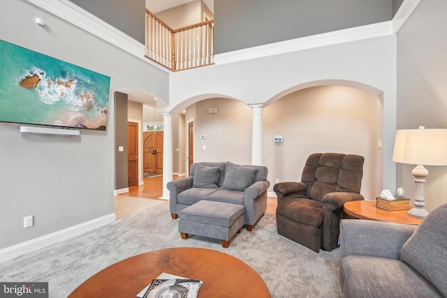 living room featuring crown molding, decorative columns, a towering ceiling, and light colored carpet