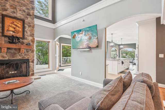 carpeted living room featuring a high ceiling, a fireplace, and sink