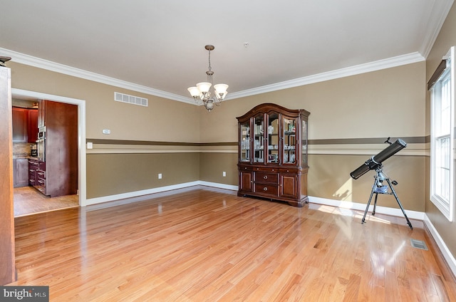 unfurnished room featuring crown molding, a chandelier, and light wood-type flooring