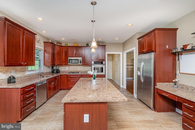 kitchen featuring light stone countertops, sink, appliances with stainless steel finishes, a center island, and pendant lighting