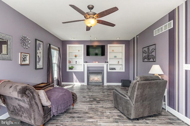 living room with ceiling fan, built in shelves, and hardwood / wood-style floors