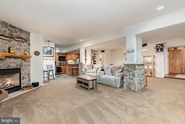 carpeted living room featuring a stone fireplace