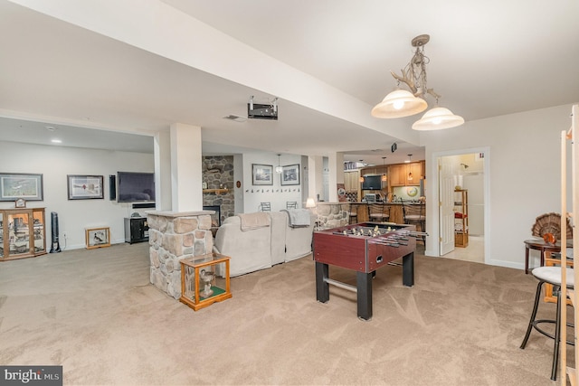 rec room featuring a stone fireplace and light colored carpet