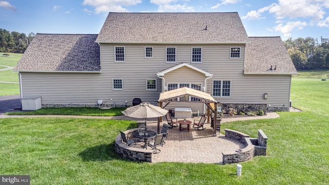 rear view of house with an outdoor fire pit, a patio, and a lawn