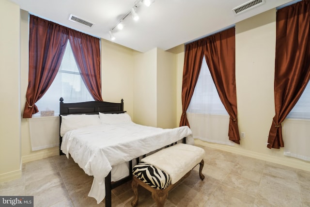 bedroom with track lighting and light tile patterned floors