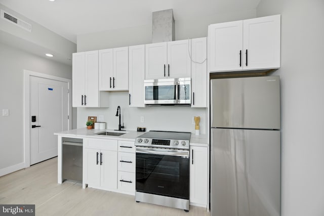 kitchen with white cabinetry, stainless steel appliances, sink, and light hardwood / wood-style floors