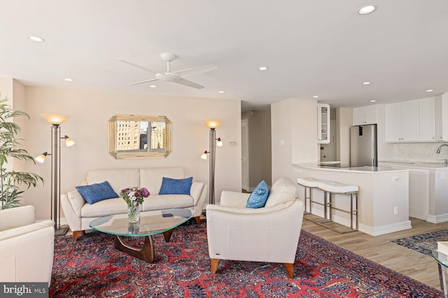 living room featuring light hardwood / wood-style floors, sink, and ceiling fan