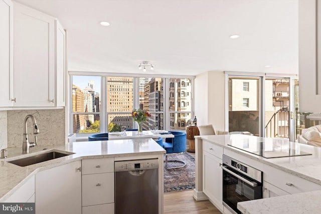 kitchen with appliances with stainless steel finishes, light wood-type flooring, white cabinetry, and sink