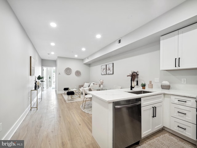 kitchen featuring stainless steel dishwasher, kitchen peninsula, sink, light wood-type flooring, and white cabinets