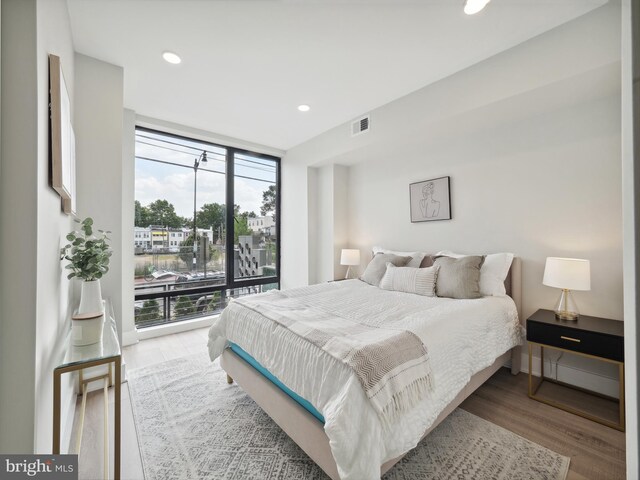 bedroom featuring light wood-type flooring and expansive windows