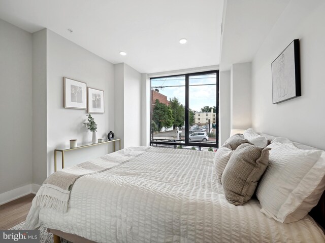 bedroom with access to exterior and hardwood / wood-style floors