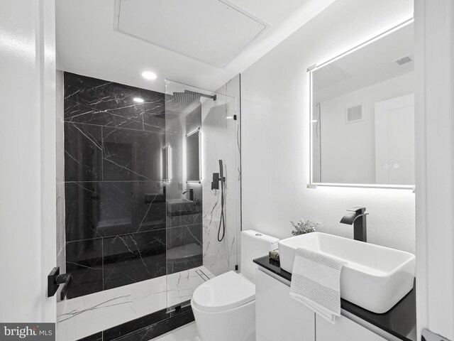 bathroom featuring tiled shower, toilet, and vanity