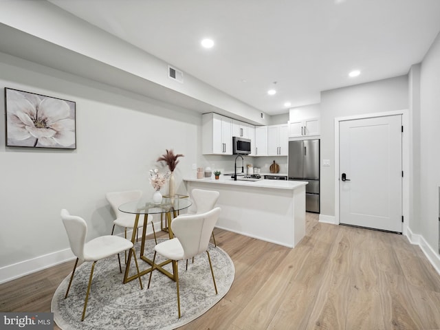 dining area with sink and light hardwood / wood-style floors