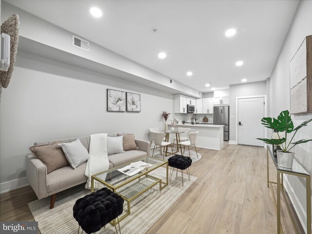 living room featuring sink and light hardwood / wood-style floors