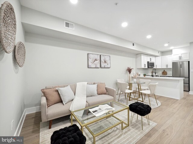 living room featuring light wood-type flooring and sink