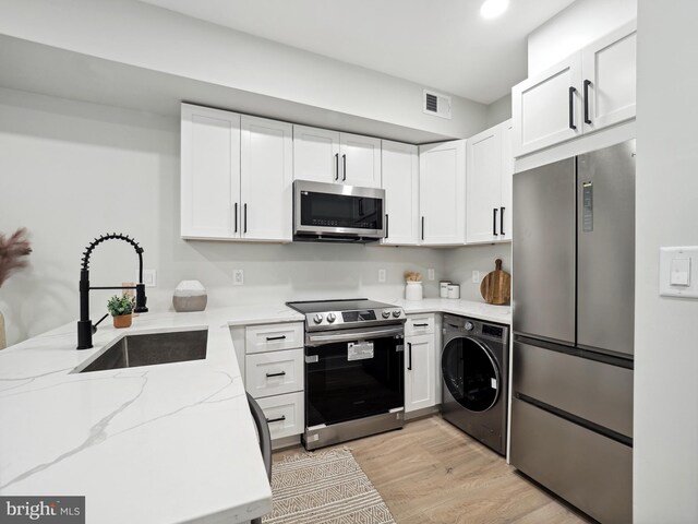 kitchen featuring stainless steel appliances, sink, washer / dryer, white cabinets, and light hardwood / wood-style floors