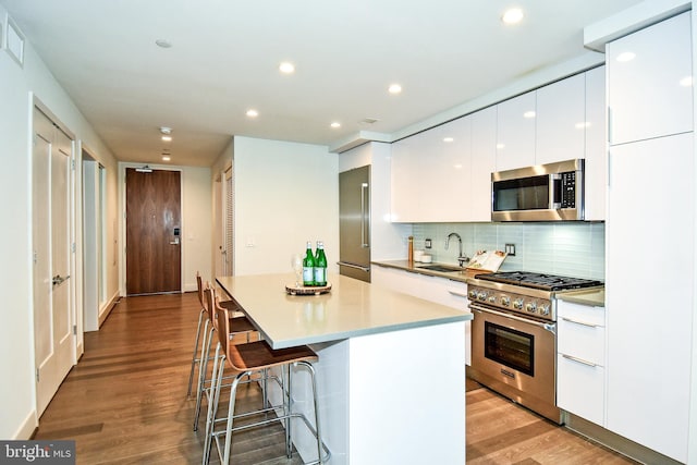 kitchen with light wood-type flooring, white cabinets, sink, and high quality appliances