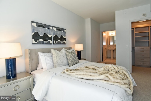 carpeted bedroom with a closet, ensuite bath, and a spacious closet