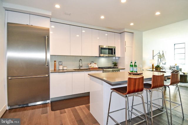 kitchen featuring a center island, sink, white cabinets, appliances with stainless steel finishes, and dark hardwood / wood-style flooring