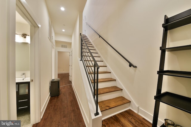 stairway with hardwood / wood-style floors and sink