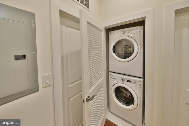 clothes washing area with electric panel and stacked washer / drying machine