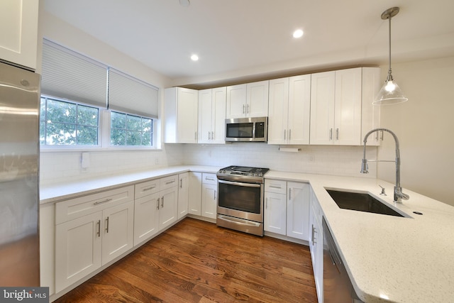 kitchen with white cabinetry, pendant lighting, stainless steel appliances, dark hardwood / wood-style floors, and sink