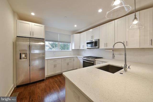 kitchen featuring decorative light fixtures, dark wood-type flooring, white cabinetry, appliances with stainless steel finishes, and light stone countertops