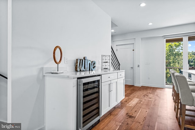 bar with white cabinets, wine cooler, and light wood-type flooring