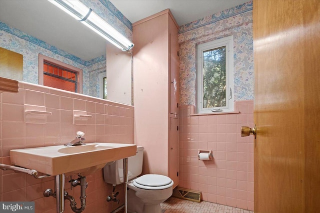 bathroom with tile patterned flooring, toilet, and tile walls