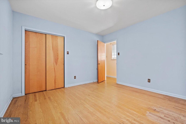 unfurnished bedroom with light wood-type flooring and a closet