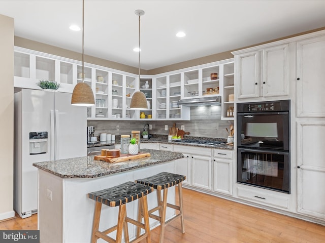 kitchen featuring white fridge with ice dispenser, double oven, decorative backsplash, and decorative light fixtures