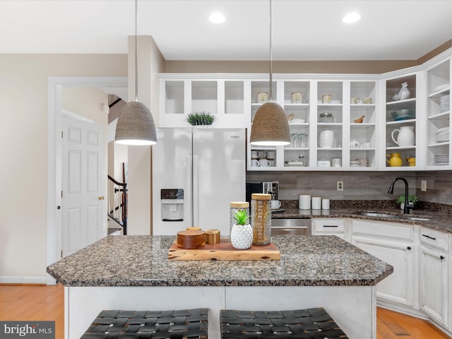 kitchen with pendant lighting, refrigerator with ice dispenser, decorative backsplash, and sink