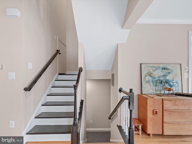 stairs featuring wood-type flooring and crown molding